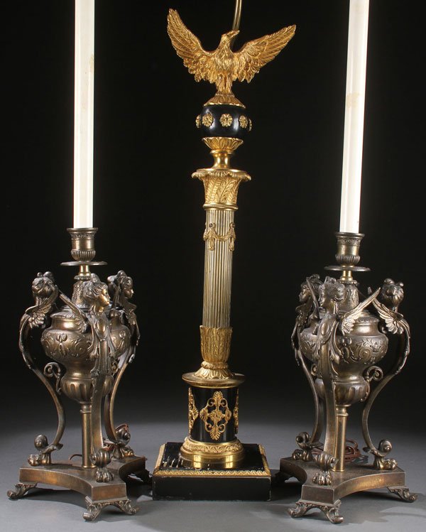 EMPIRE STYLE & NEO-CLASSIC LAMPS: AN EMPIRE REVIVAL GILT BRONZE AND EBONIZED WOOD TABLE LAMP, 20TH CENTURY. Modeled as an architectural column surmounted with the figure of a wing spread eagle. Together with a pair of Neo-Classic cast