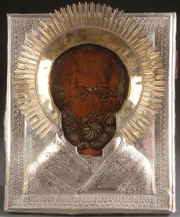 A RUSSIAN ICON OF ST. NICHOLAS, 19TH CENTURY: A RUSSIAN ICON OF ST. NICHOLAS, 19TH CENTURY. Depicted here in bust portrait form, the entire image overlaid with a heavy silver plated, repoussd and chased riza with attached halo. 14 inches x 12.25 