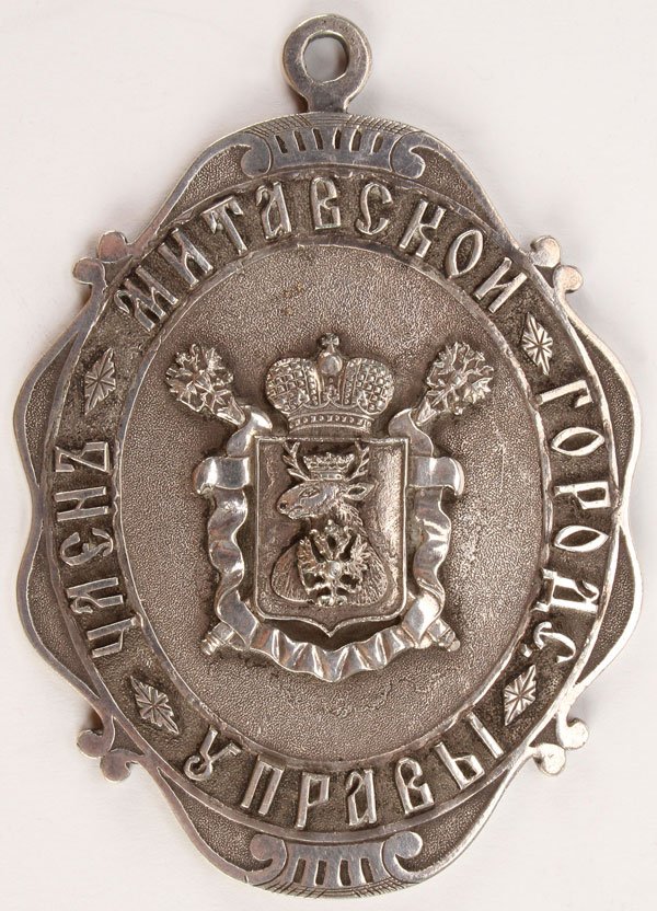 RARE IMPERIAL RUSSIAN BADGE OF CITY COUNCIL MEMBER: A RARE IMPERIAL RUSSIAN BADGE OF A CITY COUNCIL MEMBER FOR THE CITY OF MITAVA LATVIA, BUCH BROS., ST. PETERSBURG, CIRCA 1870. The large heavy silver plated bronze shield-shaped badge with finely sculp