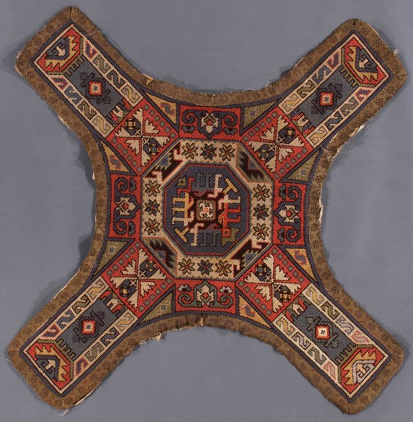 A CAUCASIAN OR ARMENIAN EMBROIDERED REMNANT: A CAUCASIAN OR ARMENIAN EMBROIDERED REMNANT, CIRCA 1900 OR EARLIER. Flat woven with hooked medallion, blossoms and S repeats on a squared cross form, possibly used for an altar cloth, complete with re