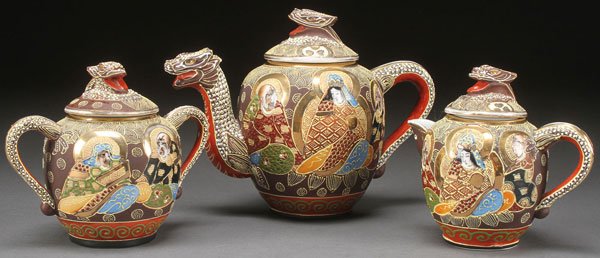 A THREE PIECE JAPANESE SATSUMA TEA SET, 20TH C: A THREE PIECE JAPANESE SATSUMA TEA SET, 20TH CENTURY. Decorated with three figures with raised enameling and gilt highlights, the tea pot with dragon form spout, red "TT" mark. Height 6.25 inches (16 