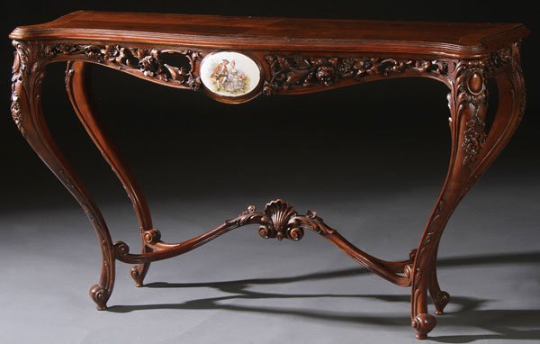 AN ITALIANTE ROCOCO STYLE CREDENZA, CIRCA 1900: AN ITALIANTE ROCOCO STYLE CREDENZA, CIRCA 1900. The openwork carved foliate skirt with central oval porcelain plaque decorated with a romantic courting scene, raised on carved cabriole legs and surmou