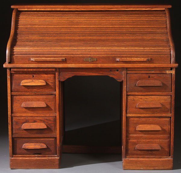 AN AMERICAN OAK S-CURVE ROLL TOP DESK: AN AMERICAN OAK S-CURVE ROLL TOP DESK, CIRCA 1900. The top section rolling back to reveal a pigeon hole compartment raised on two four drawer pedestals. Height 44.5 inches, length 48 inches, depth 20 