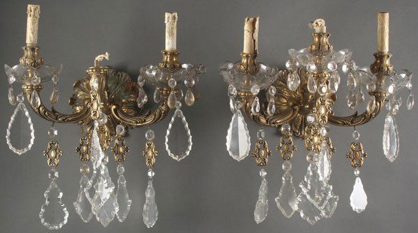 A PAIR OF ITALIANATE GILT BRONZE AND CUT CRYSTAL: A PAIR OF ITALIANATE GILT BRONZE AND CUT CRYSTAL WALL SCONCES, CIRCA 1900. Each with acanthus leaf form wall plate supporting three scrolled foliate candle arms with glass bobeches and cut crystal pen