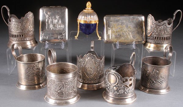 RUSSIAN SOVIET DECORATIVE ARTS: A GROUP OF TEN RUSSIAN SOVIET PERIOD DECORATIVE ARTS, CIRCA 1975-2000. Comprising seven silver plated metal tea glass holders, some with traditional 19th century designs (troika scenes and floral scen