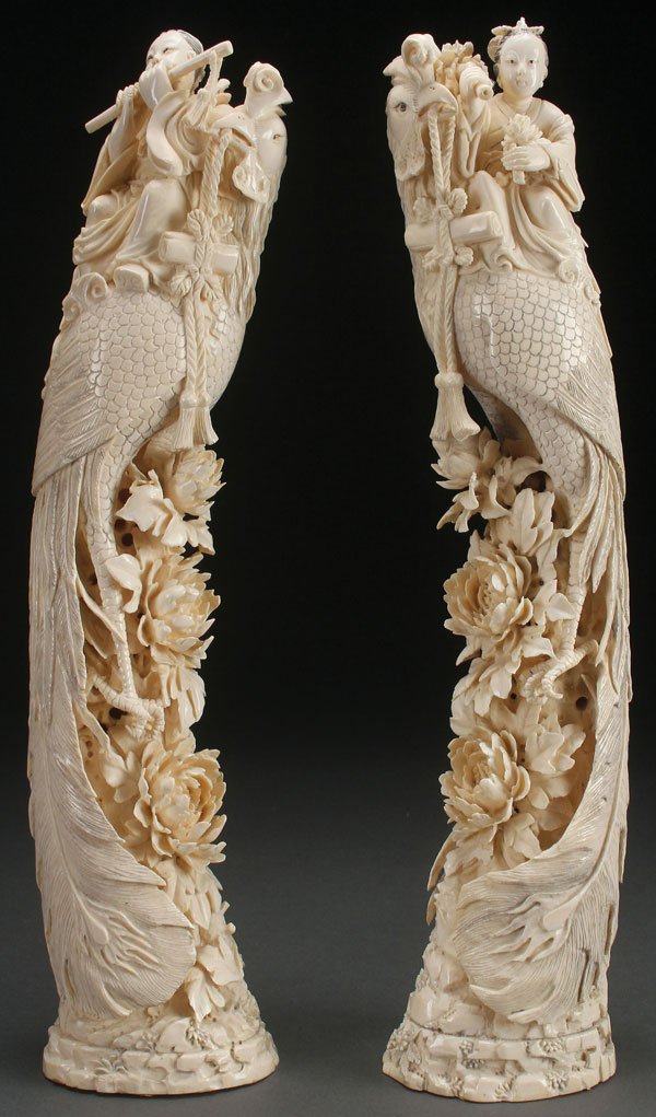PAIR OF CHINESE FIGURAL CARVED IVORY TUSKS: A PAIR OF LARGE AND IMPRESSIVE CHINESE FIGURAL CARVED IVORY TUSKS, CIRCA 1920. Each modeled as a phoenix bird with elongated tail resting on reticulated and extending lotus blossomed base and with eac