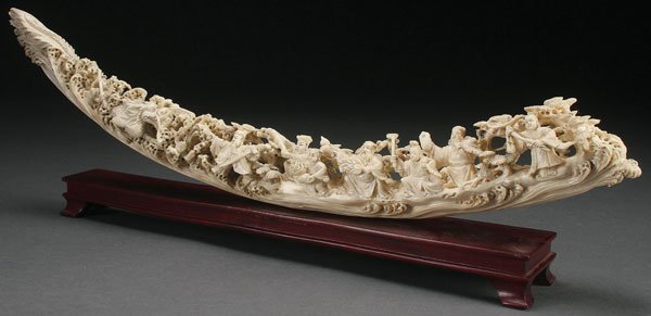 CHINESE CARVED IVORY IMMORTALS TUSK, CIRCA 1930: A CHINESE CARVED IVORY “IMMORTALS” TUSK, CIRCA 1930. Fully carved and pierced in the round with a scene depicting eight Immortals, a dragon in waves and pine trees. Length 20 inches (51 cm). The o