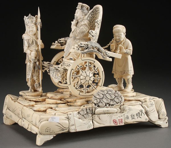 A LARGE CHINESE CARVED IVORY FIGURAL GROUP: A LARGE CHINESE CARVED IVORY AND BONE FIGURAL GROUP, CIRCA 1925. Depicting a seated Emperor in wheeled throne chair pushed by an attendant and with armored guardian at lead, fully carved in the round 