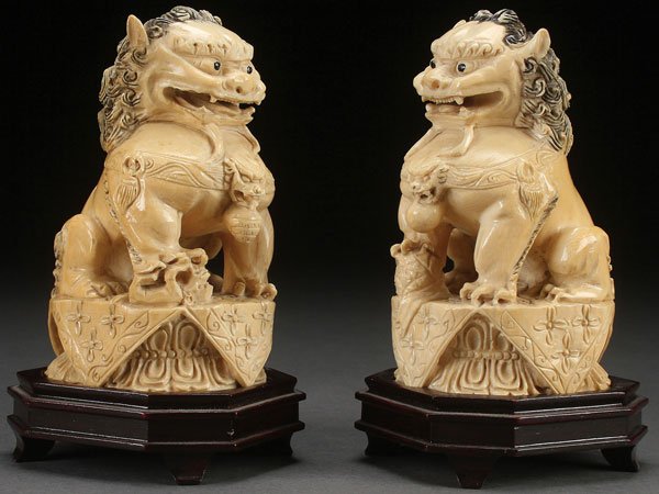 A PAIR OF CHINESE CARVED IVORY TEMPLE FOO DOGS: A FINE PAIR OF CHINESE CARVED IVORY TEMPLE “FOO” DOGS, PROBABLY QING DYNASTY. Each well carved in archaic form depicting the sitting beasts on a double lotus throne and with incised character mark