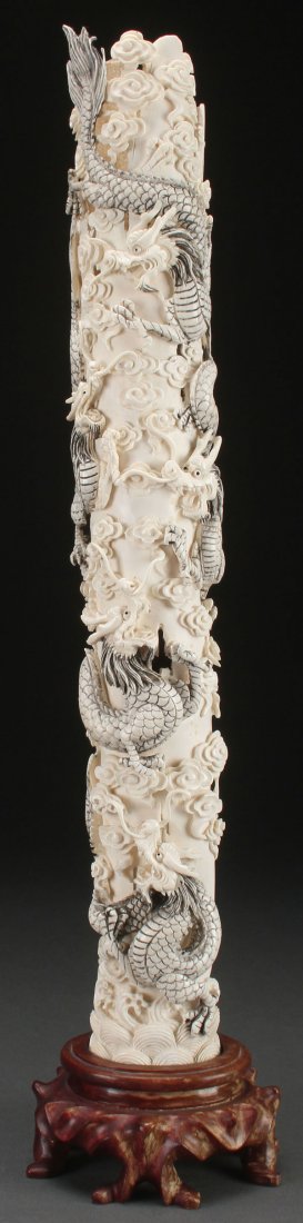 A CHINESE CARVED IVORY TUSK, CIRCA 1930: A CHINESE CARVED IVORY TUSK, CIRCA 1930. Carved in deep and pierced extended relief with five undulating dragons amidst stylized cloud forms, the base with incised Reign Mark and raised on a fitted ca