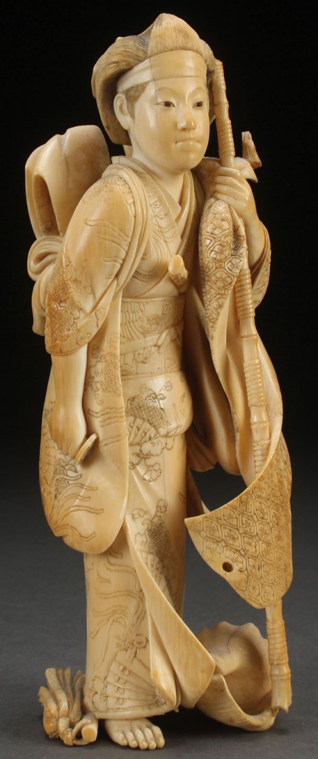 JAPANESE CARVED IVORY OKIMONO, EDO-MEIJI: A JAPANESE CARVED IVORY OKIMONO OF AN ONNA-BUGEISHA, EDO-MEIJI PERIOD (19TH CENTURY). Well carved with garments in detailed relief, standing holding a staff beside a conch shell with arrow fragments, 