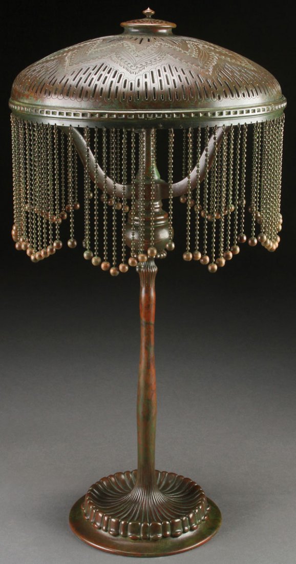 TIFFANY STUDIOS BRONZE "MOORISH" TABLE LAMP: A TIFFANY STUDIOS PATINATED BRONZE “MOORISH” TABLE LAMP, EARLY 20TH CENTURY. The bronze elongated “candlestick” base surmounted with three scrolled arms supporting a circular ring with a curta
