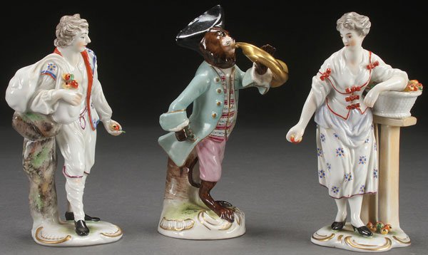 A GROUP OF THREE VICTORIAN PORCELAIN FIGURES.: A GROUP OF THREE VICTORIAN PORCELAIN FIGURES. Comprising a Meissen style figural monkey with horn and a pair of Ludwigsburg figures of a man and woman with apples. The largest 5.5 inches (14 cm).
