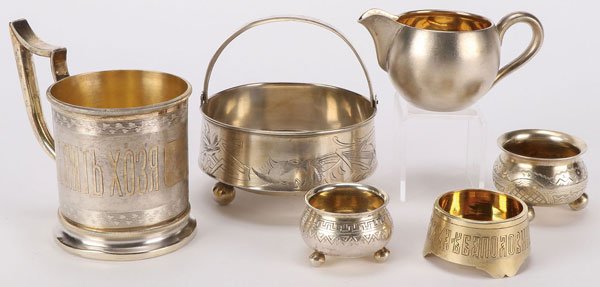SIX RUSSIAN SILVER ITEMS CIRCA 1880-1917: AN INTERESTING GROUP OF SIX RUSSIAN SILVER ITEMS, 1880-1917. Comprising a silver-gilt tea glass holder with flared foot, the sides engraved with Russian proverb, chased banding of intertwined leaves a