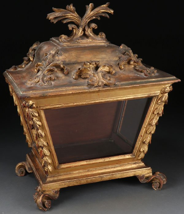 A CARVED AND GILT WOOD ROCOCO RELIQUARY CASKET: A LARGE CARVED AND GILT WOOD ROCOCO RELIQUARY CASKET, ITALIAN, 18TH CENTURY. Resting on four carved scroll feet with flared sides, the corners with carved bellflowers, and with glazed exposition windo