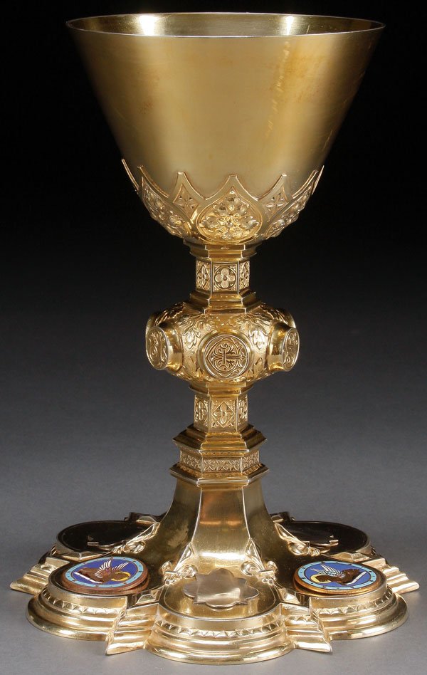 A GOTHIC STYLE SILVER & ENAMEL CHALICE AND PATEN: A GOTHIC STYLE SILVER AND ENAMEL CHALICE AND PATEN, FRENCH, 1899. The quatrefoil base with stepped sides, fleur-de-lis and champlevé enamel medallions as well as three blank reserves. The bulbous cen