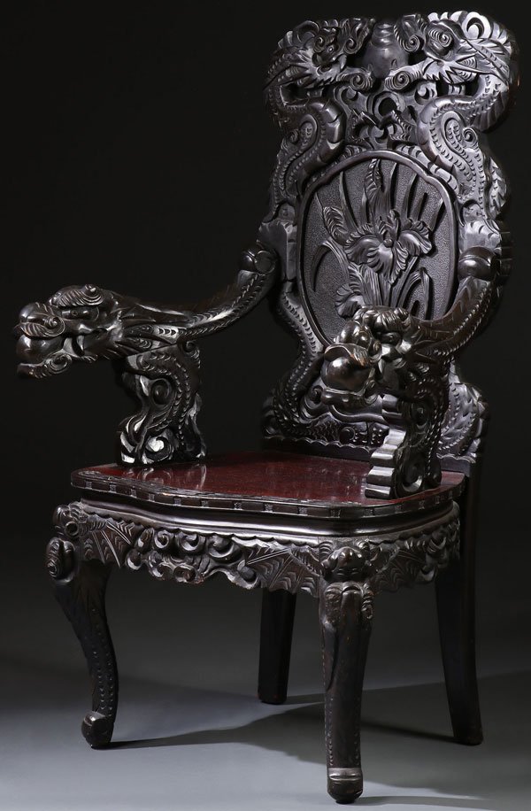A JAPANESE CARVED EBONIZED WOOD DRAGON ARMCHAIR: A JAPANESE CARVED EBONIZED WOOD DRAGON ARMCHAIR, FIRST HALF OF THE 20TH CENTURY. Approximate height 45 inches (114.3 cm). The backrest ornately carved in open work with dragons, cattails, and floral f
