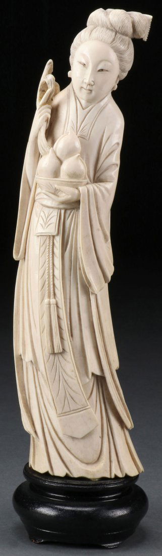 CHINESE CARVED IVORY FIGURE OF KWAN-YIN, CIRCA 1900: A FINE CHINESE CARVED IVORY FIGURE OF KWAN-YIN, CIRCA 1900 of naturalistic tusk shape and well carved with folded garments depicted holding peaches and wheat. The verso with incised red seal mark. Fur