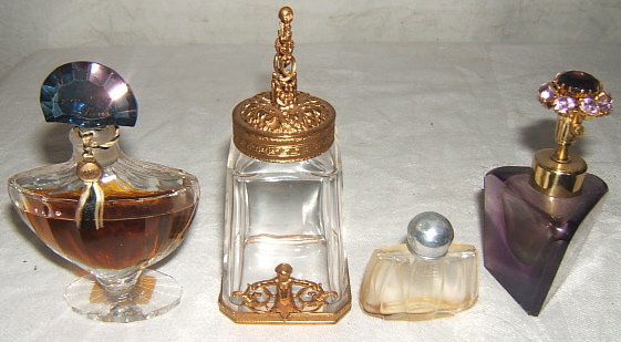 4 Antique Perfume Bottles Guerlain Paris: From left to right: Guerlain Paris Etched on finial cap with tag on based. Approx. size: 2 5/8" x 3 3/4". Brass Filigree Bottle with Cherub Figure. The crystal rim has some chips. Approx. size: 2" x 4