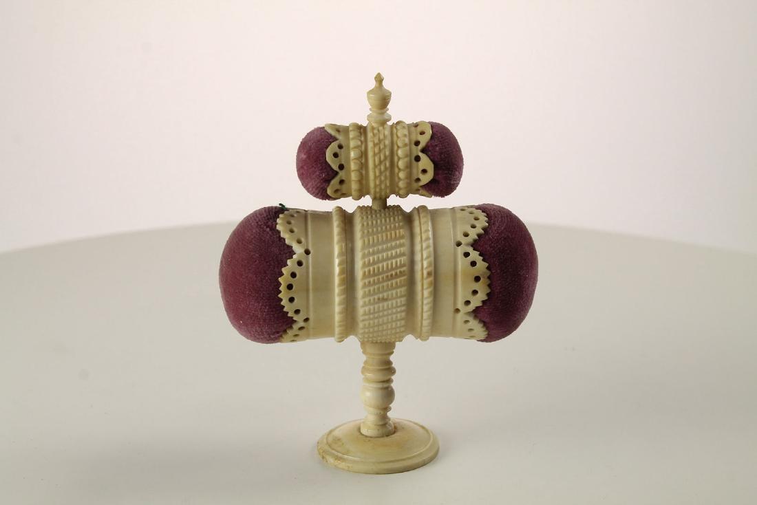 Rare quadruple bone pincushion with Tape: An extremely rare quadruple pin cushion with centre tape measure The top turning to pull tape in or out the cushions in dusty pink The body made of heavily carved bone with four delicately carved side