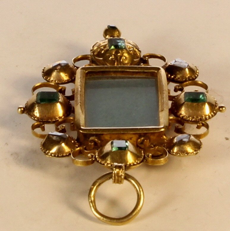 Emerald and gold tabernacle pendant: A Spanish or Portuguese emerald and gold tabernacle pendant Of tabernacle form, the vacant glazed rectangular centre bordered by emeralds and gold scrollwork, length 5cm, gross weight 11.1g for 360 im
