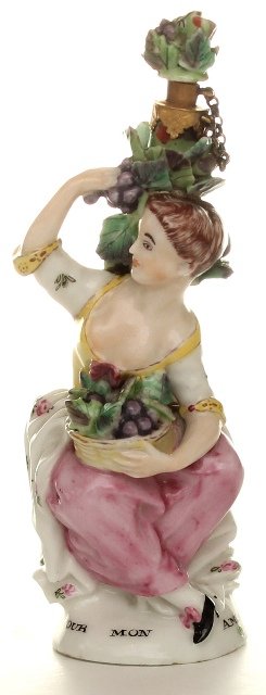 A chelsea scent bottle. English c1760: A fine example of a Chelsea porcelain scent bottle, in the form of a lady holding a basket of fruit, with gold mounts to the neck, the base painted with a rose. English c1760