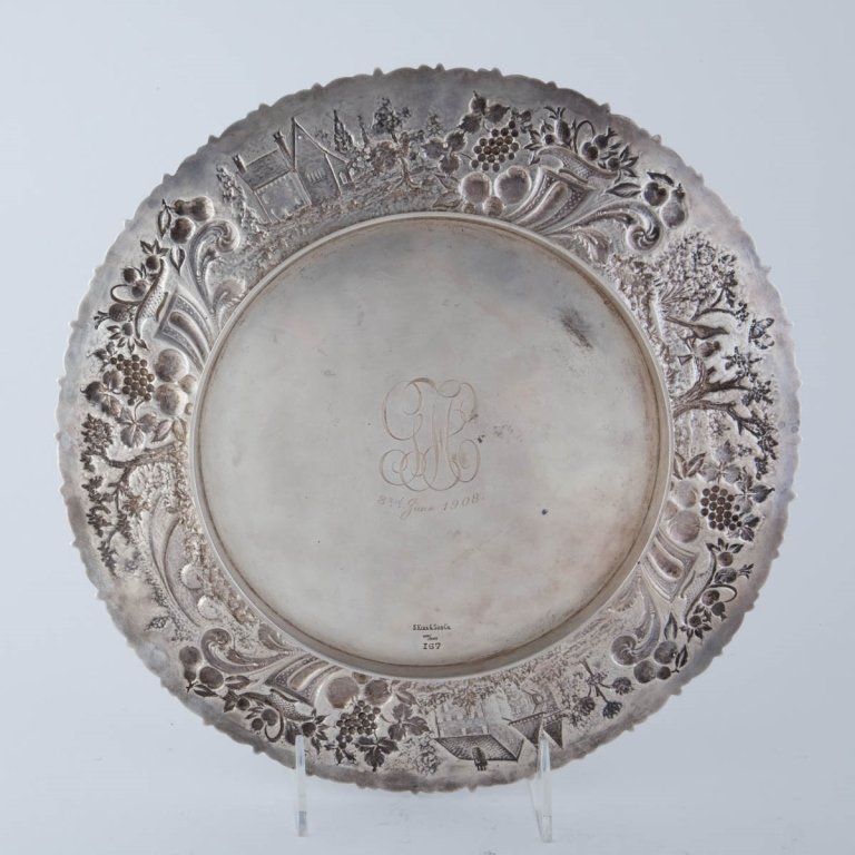 A Large Sterling Silver Platter: 1908 Applied floral rim on stippled ground, with foliage, birds, fruit cornucopia and buildings, made by S. Kirk & Son in Baltimore Mono on reverse and engraved June 3, 1908. Weight; 18.48 troy oz dia