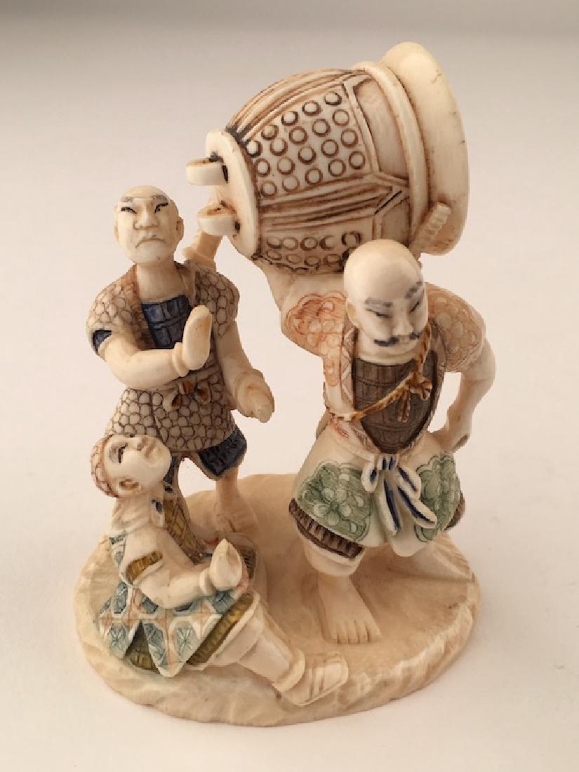 A carved figurine of three men with a large bell. (1 of 8)