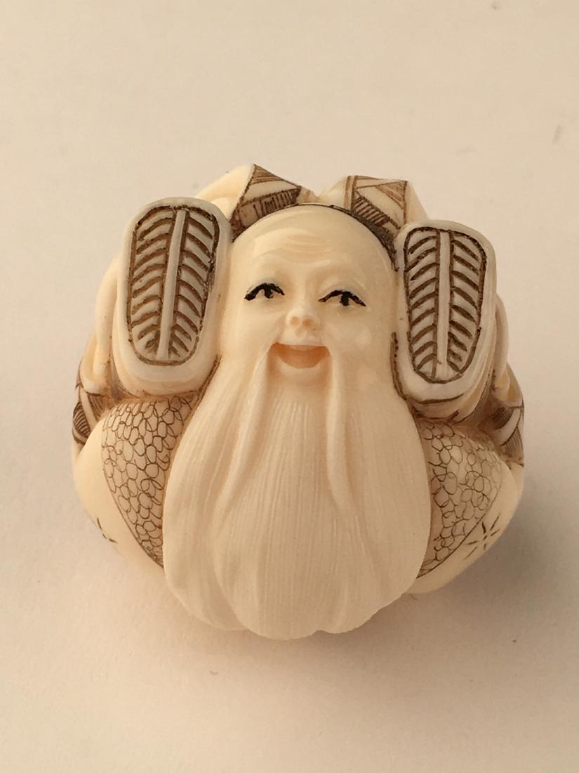 A carved netsuke figure of a man with his feet wrapped (1 of 6)