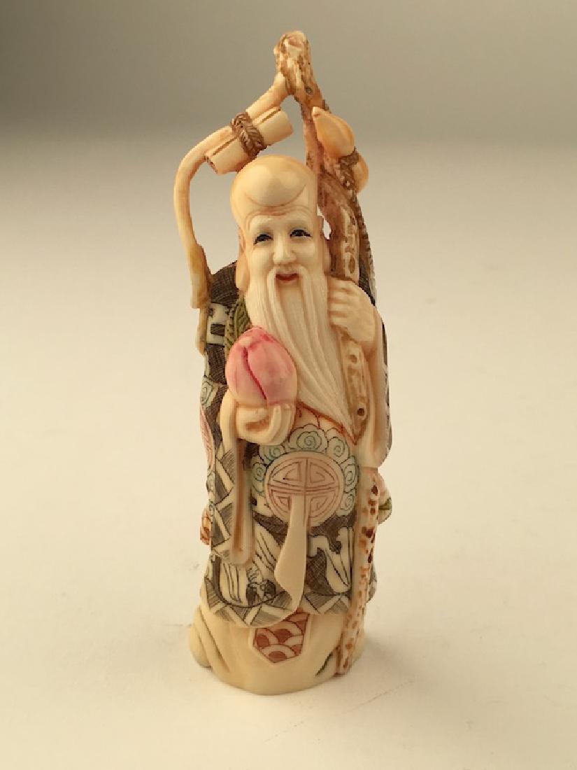 A patinated carved figure of a wise man standing: A patinated carved figure of a wise man standing holding a staff and a piece of fruite.Signed on the bottom.Height 4 1/2 inches.