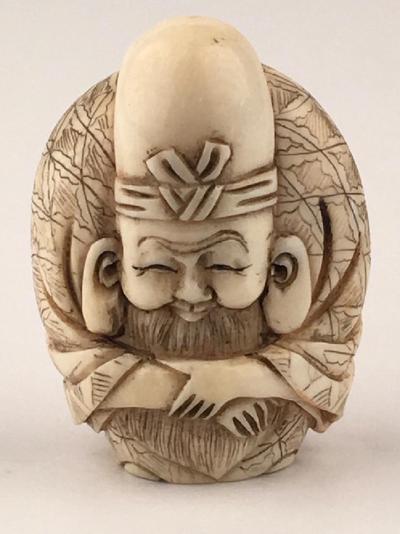 A carved Netsuke figure of a man with his arms crossed. (1 of 5)