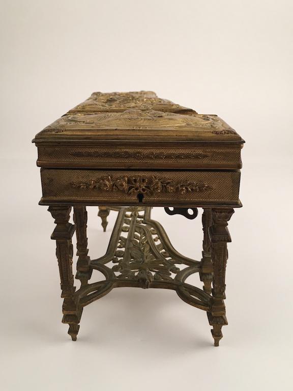 Antique bronze music box as a grand piano.: Antique bronze music box as a grand piano. Decorated with a foliate motiff as well as birds and a musical theme. Length 8 3/4 inches. Width 4 1/8 inches. Height 5 inches.