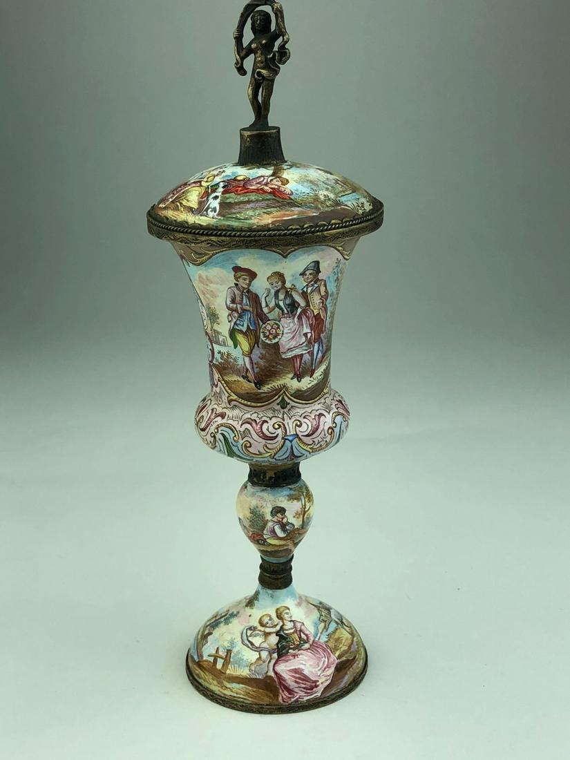 Antique Viennese enameled silver cup and cover.: Antique Viennese enameled silver cup and cover. Decorated with romantic scenes with a top cover finial depicting a lady with a garland over her head. Overall height 6 3/4 inches.