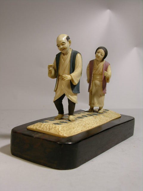 IVORY CARVING OF A MAN AND WOMEN IN A RICE PATTY.