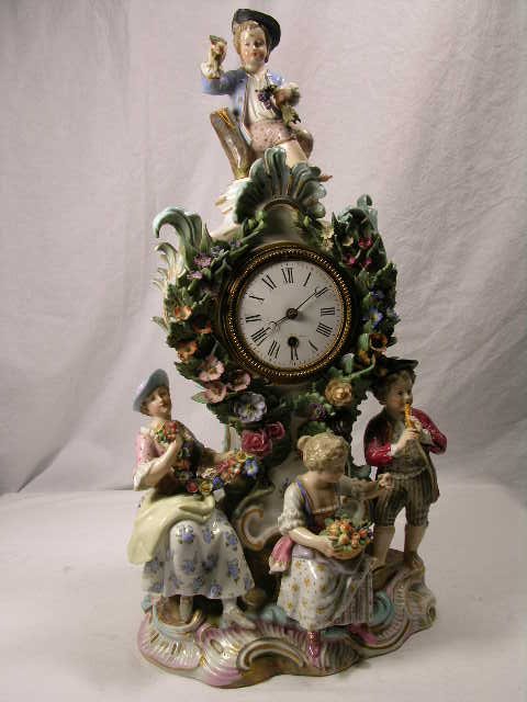PORCELAIN MANTEL CLOCK WITH FOUR FIGURINES. CHIP - 4