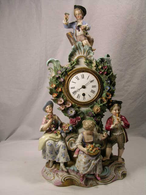 PORCELAIN MANTEL CLOCK WITH FOUR FIGURINES. CHIP - 6