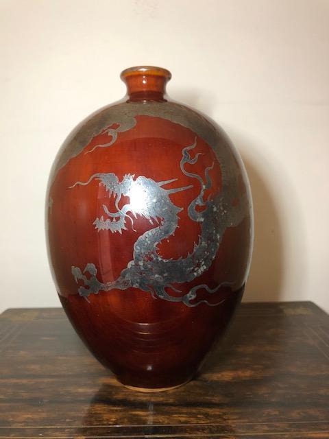 Japanese porcelain vase decorated with a silver dragon: Japanese porcelain vase decorated with a silver dragon on a deep rust color ground. 20 th century. Impressed mark on bottom. Height 7 1/2 inches. Diameter 4 7/8 inches.