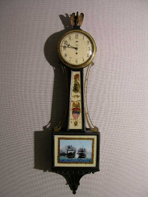 A WILLARD BANJO CLOCK STAMPED "TIFFANY AND COMPANY : A WILLARD BANJO CLOCK STAMPED "TIFFANY AND COMPANY NEW YORK". DECORATED WITH AN AMERICAN EAGLE AS THE TOP FINIAL AND REVERSED PAINTED TWO WAR SHIPS THE US CONSTITUTION AND GUERRIERE" SPRING DRIVEN CHE