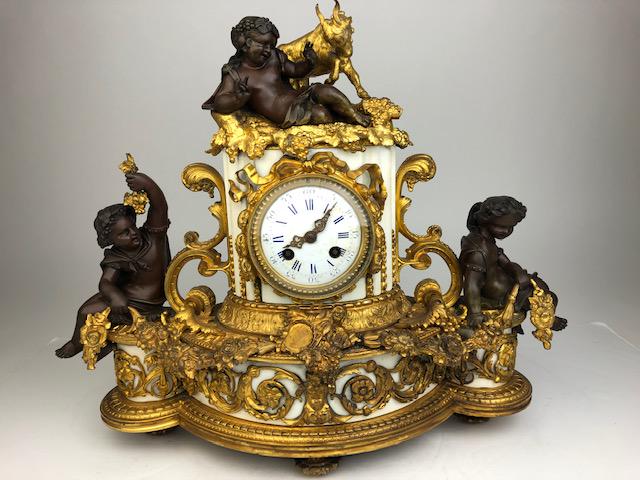 Antique French bronze and gold gilt marble mantle: Antique French bronze and gold gilt marble mantle clock. the clock with young children to each side as well as another reclining with an playing goat. Supported on four round feet. Height 15 inches. L