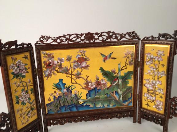 Fine Chinese cloisonné three-fold table screen,: Fine Chinese cloisonné three-fold table screen, the center panel with birds in a flowering garden, each end panel with flowers and butterfly, all enclosed in a carved hardwood frame with silver w