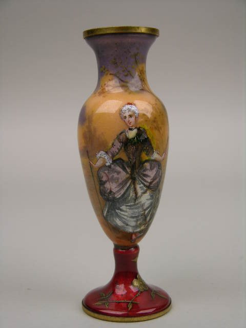 A FRENCH ENAMELLED VASE.: A FRENCH ENAMELLED VASE. A BEAUTIFUL VASE PAINTED WITH AN ELEGANT WOMAN HOLDING A FAN IN HER RIGHT HAND AND A CANE IN THE OTHER WITH FLOWERS NEAR THE BASE. SIGNED ""VILE". HEIGHT 4".