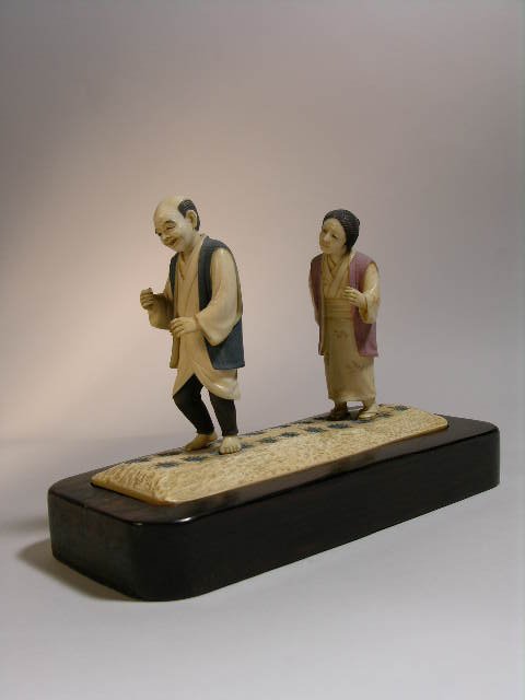 IVORY CARVING OF A MAN AND WOMAN IN A RICE PATTY.
