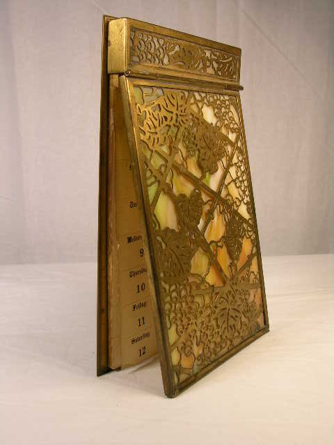 TIFFANY STUDIOS PAD HOLDER IN THE "GRAPE VINE" PA: TIFFANY STUDIOS PAD HOLDER IN THE "GRAPE VINE" PATTERN WITH CARMEL COLOR GLASS. STAMPED "TIFFANY STUDIOS NEW YORK 1022". SOME PAGES OF 1925 CALENDAR. ( SEPT. 6 1925 TO DEC.31 1925). LENGTH 7 1/2", WID