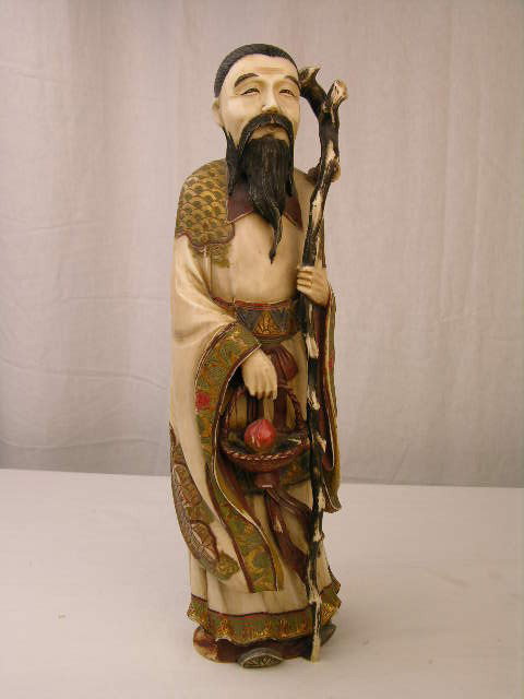 ANTIQUE JAPANESE IVORY CARVING.: ANTIQUE JAPANESE IVORY CARVING. THIS IS A CARVED AND POLYCHROME JAPANESE MAN WITH A LONG BEARD HOLDING A STICK IN ONE HAND AND A BASKET WITH A LARGE FRUIT IN THE OTHER. OVERALL HEIGHT 12". SIGNED.