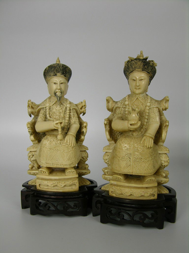 A PAIR OF CARVED IVORY CHINESE FIGURES.: AN EMPEROR AND EMPRESS CARVED IVORY CHINESE FIGURES.EACH FIGURE IN FLOWING COURT ROBES HOLDING ROYAL BEADS.THE EMPRESS HOLDING A GIFT IN HER RIGHT HAND.EACH OF THE PAIR MOUNTED ON A WOOD CARVED BASE.E