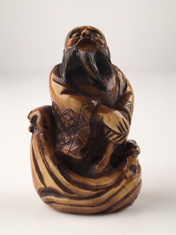 Japanese carved Netsuke of a man with a cane looking up.: Japanese carved Netsuke of a man with a cane looking up. Signed. Height 2 1/4 inches.