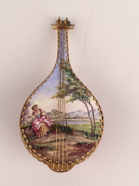Austrian Viennese enamel pill box in the shape of a mandolin: Austrian Viennese enamel painted pill box in the shape of a mandolin with a wind up music box painted with a scene of a women petting a young lamb.Length 5 inches.