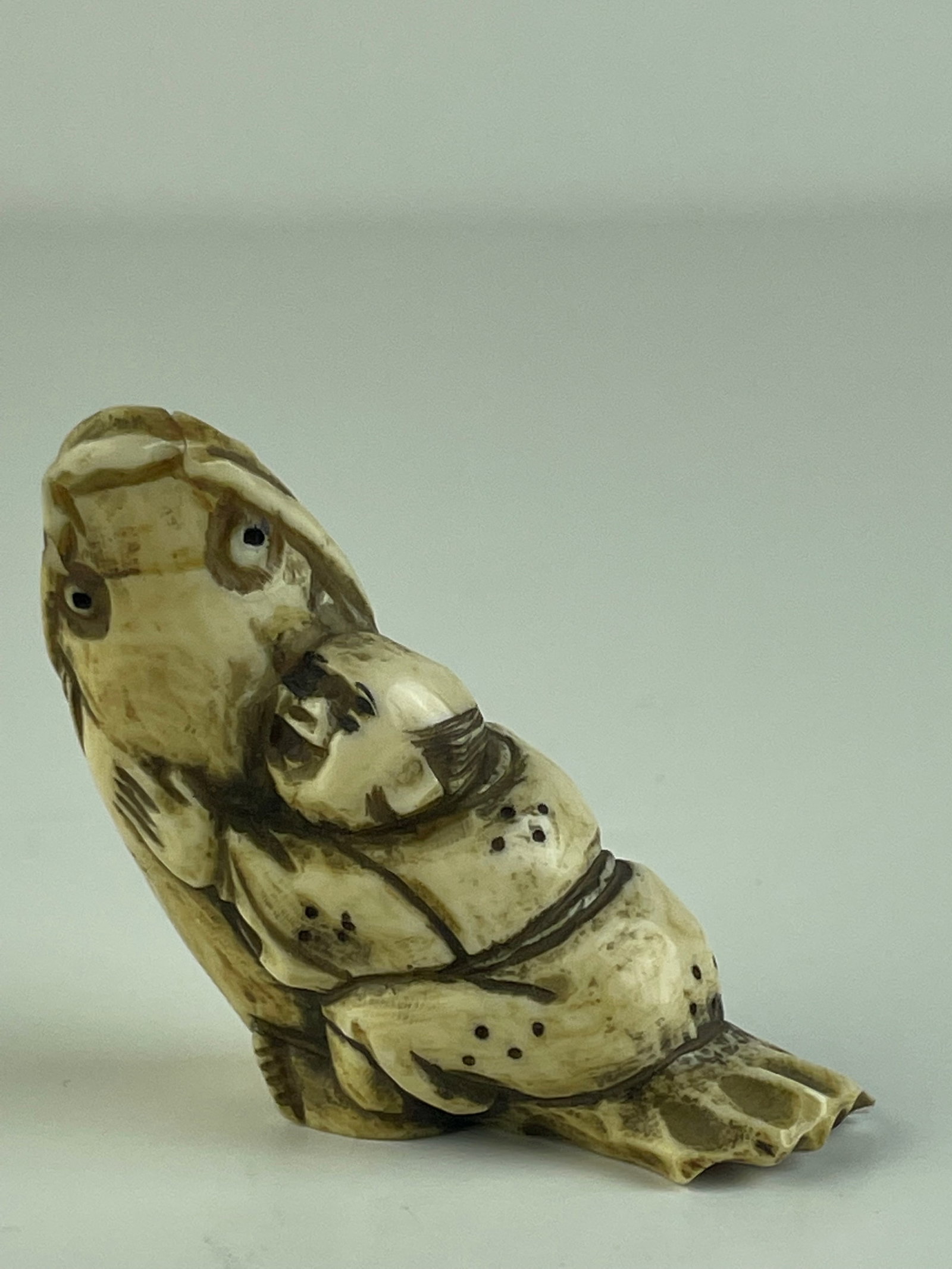Antique carved Japanese Netsuke.: Antique carved Japanese Netsuke. Carved as a man riding on a fish. Height 2 inches.