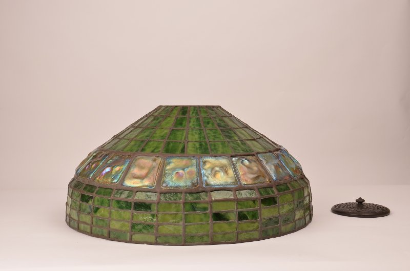 Very good Tiffany era turtleback tile and geometric: Very good Tiffany era turtleback tile and geometric lamp shade, 20th century, unsigned. The shade has a band of 20 iridescent green 'turtleback' tiles and mottled green geometric ground. Diameter: 16"
