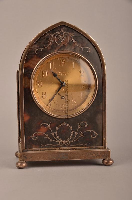 Tortoiseshell lancet clock with a Chelsea movement.: Tortoiseshell lancet clock with a Chelsea movement. The face of the clock marked "Tiffany Studios New York". Inlaid with silver decorations. Hallmarked on the full opening door. All supported on four 